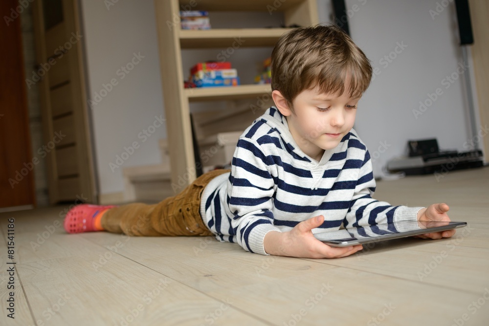 boy lying on the floor and uses his tablet boy lying on the floor and uses his tablet