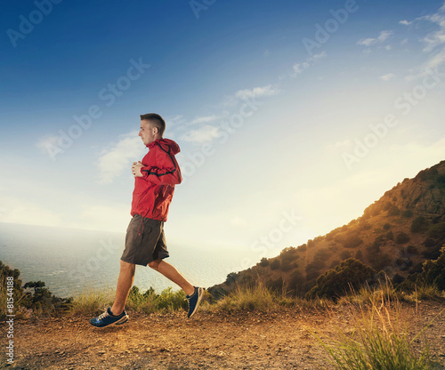 Man jogging on a rural road during sunset in the mountains. © kuznetsov_konsta