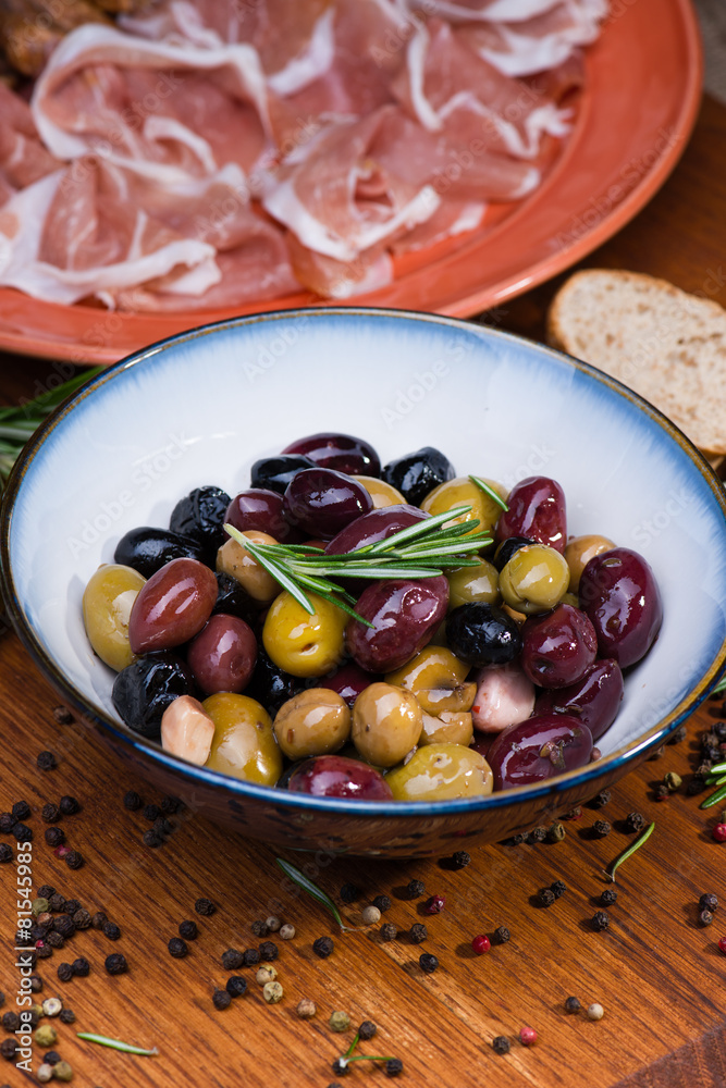 Olives in bow with prosciutto on wooden table Olives in bow with prosciutto on wooden table