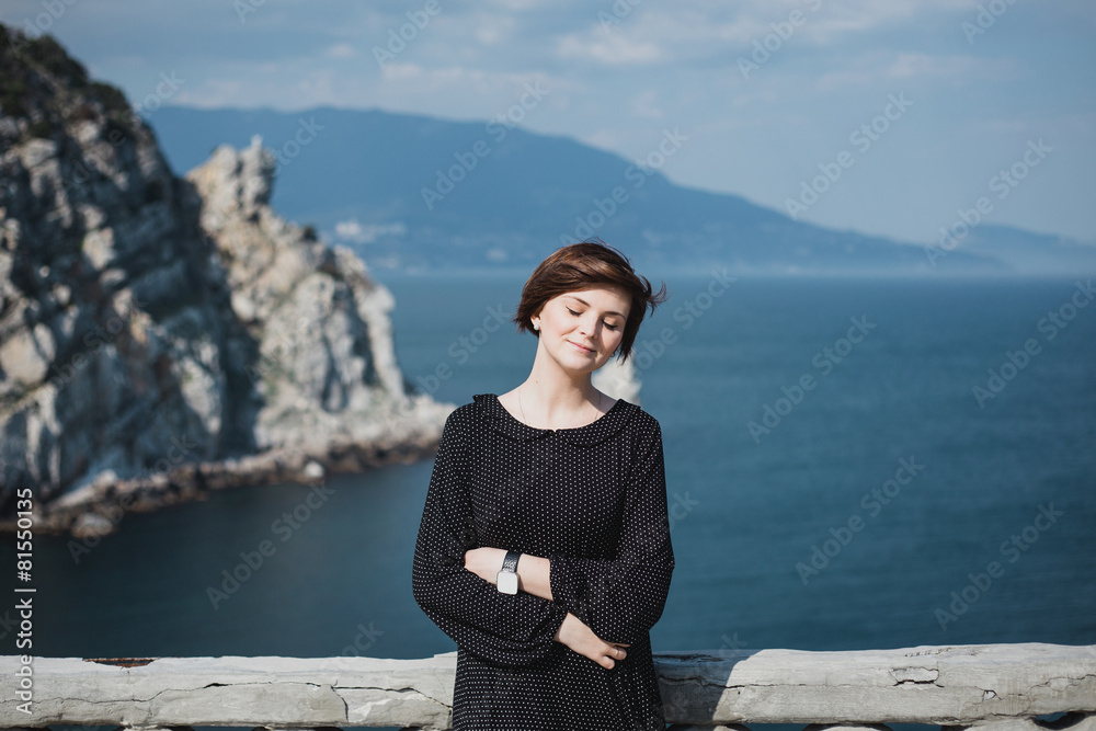 Pretty woman standing on a balcony with beautiful view Pretty woman standing on a balcony with beautiful view