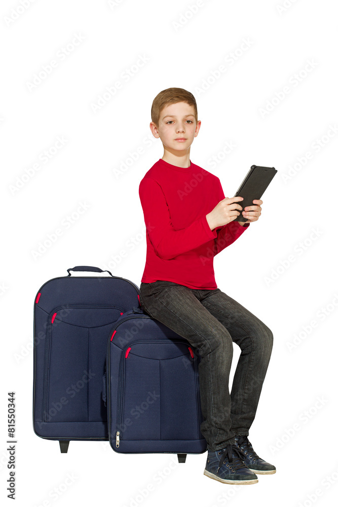 Boy sitting on travel bags holding tablet pc isolated on white Boy sitting on travel bags holding tablet pc isolated on white