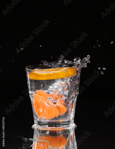 Slice of lemon splashing into a glass of water with