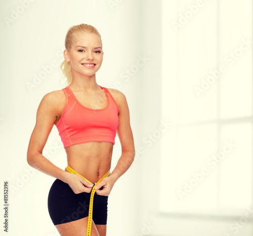 smiling sporty woman with measuring tape © Syda Productions