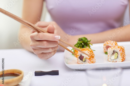 close up of woman eating sushi at restaurant