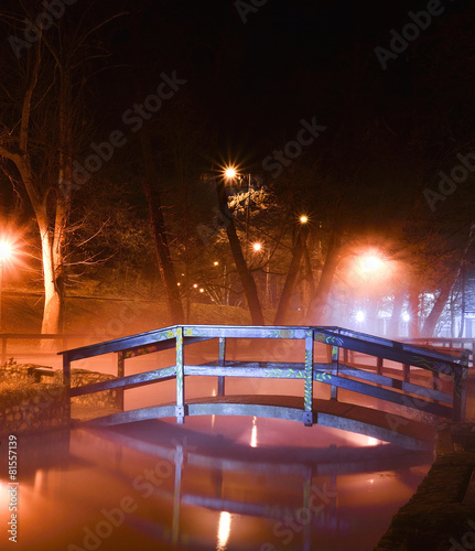 Wooden bridge over the lake, illuminated at night in Miskolcapolca, Hungary photo