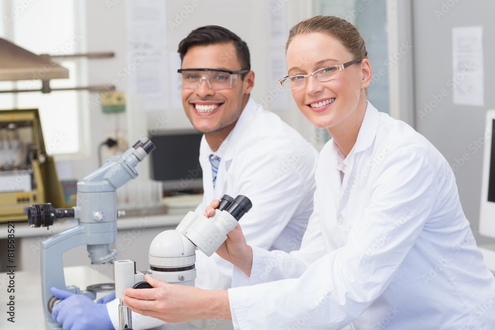 Happy scientists using microscope Happy scientists using microscope