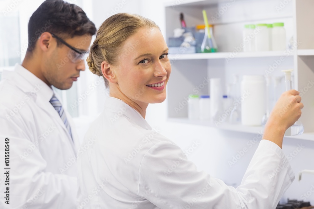 Smiling scientist looking at camera and holding a beaker Smiling scientist looking at camera and holding a beaker