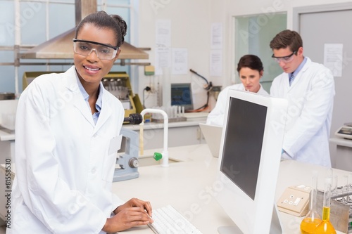 scientist smiling at camera while colleagues working together
