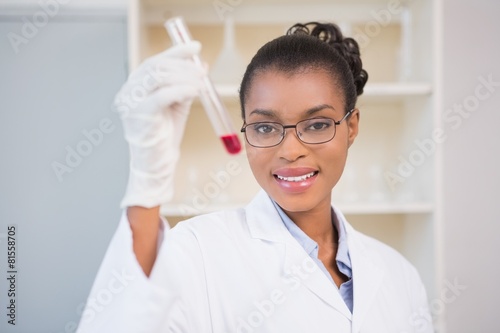 Smiling scientist showing test tube with red fluid