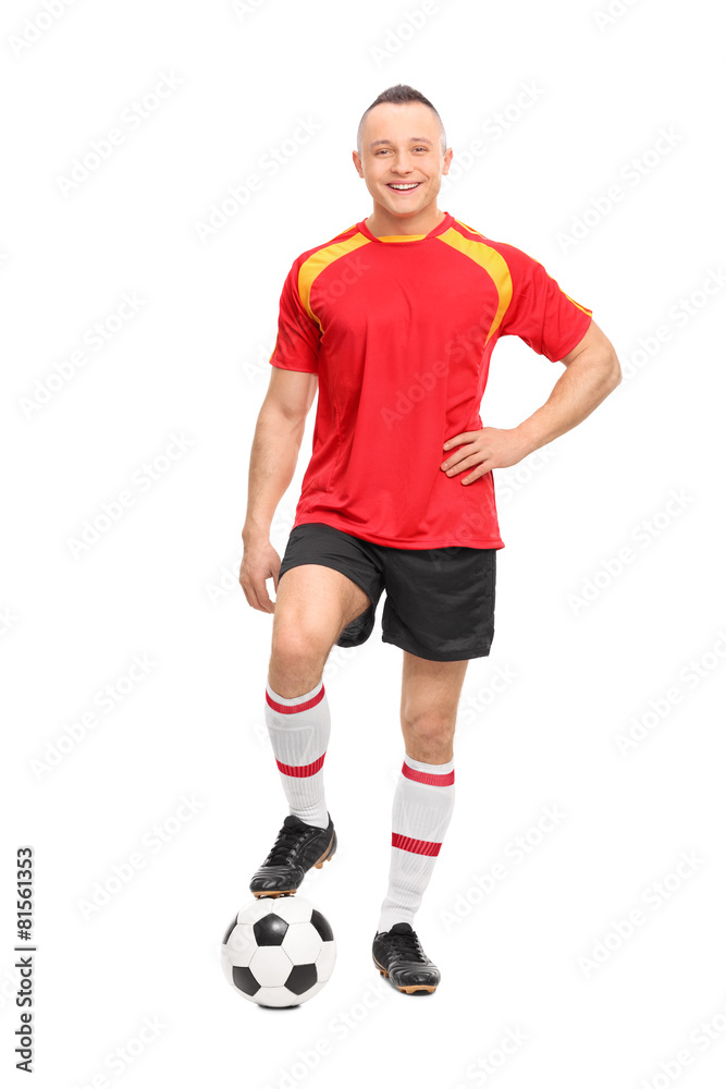 Young male soccer player standing over a ball