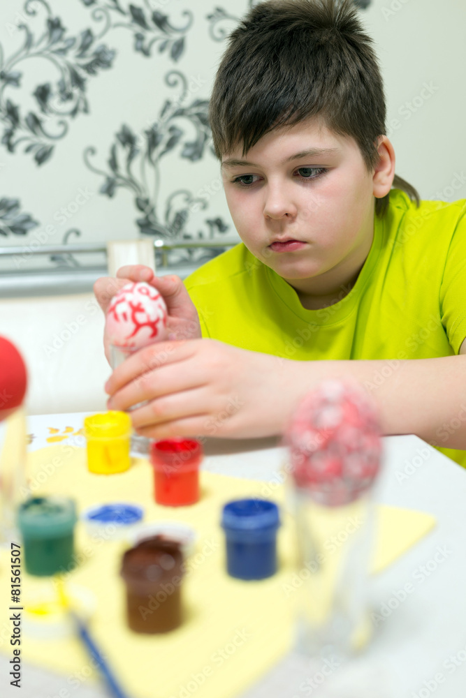 boy paints the Easter eggs with a brush boy paints the Easter eggs with a brush