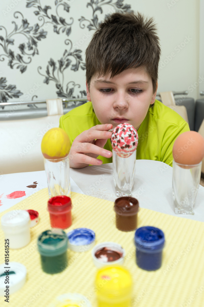 boy paints the Easter eggs with a brush boy paints the Easter eggs with a brush