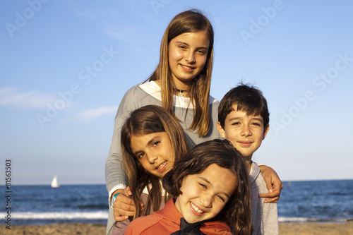 Ni  os en la playa con velero al fondo