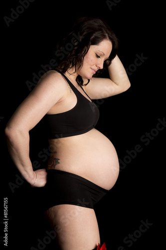 pregnant woman in black sports bra and shorts stand side look do