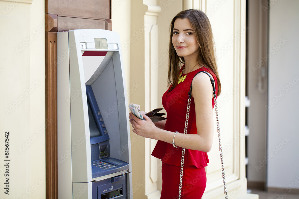 Young woman in red dress using an automated teller machine Young woman in red dress using an automated teller machine