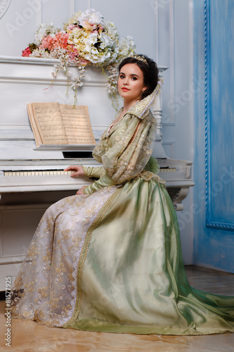 Photography queen in royal dress near the piano