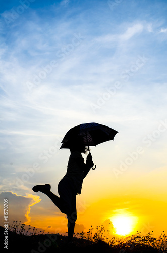 Motion blur jumping Umbrella girl with sunset silhouette