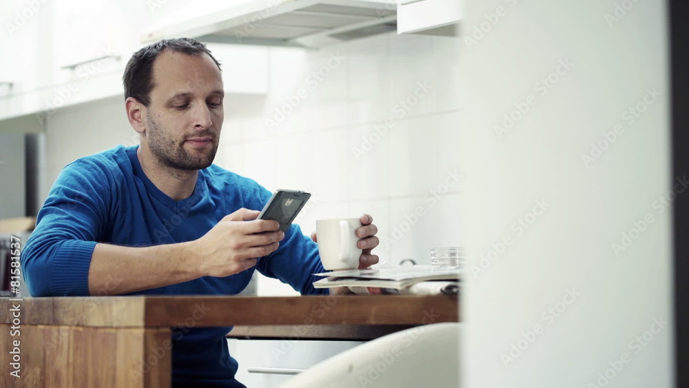 Young man using smartphone and drinking coffee by table Young man using smartphone and drinking coffee by table