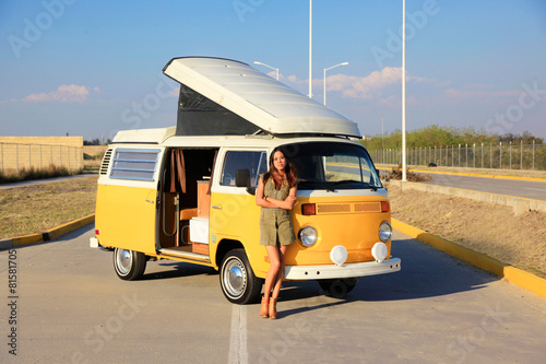 Beautiful woman standing in front of a yellow camper