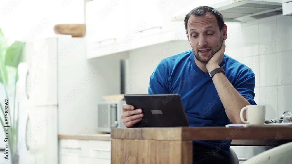 Man chatting on tablet computer and drinking coffee by table Man chatting on tablet computer and drinking coffee by table