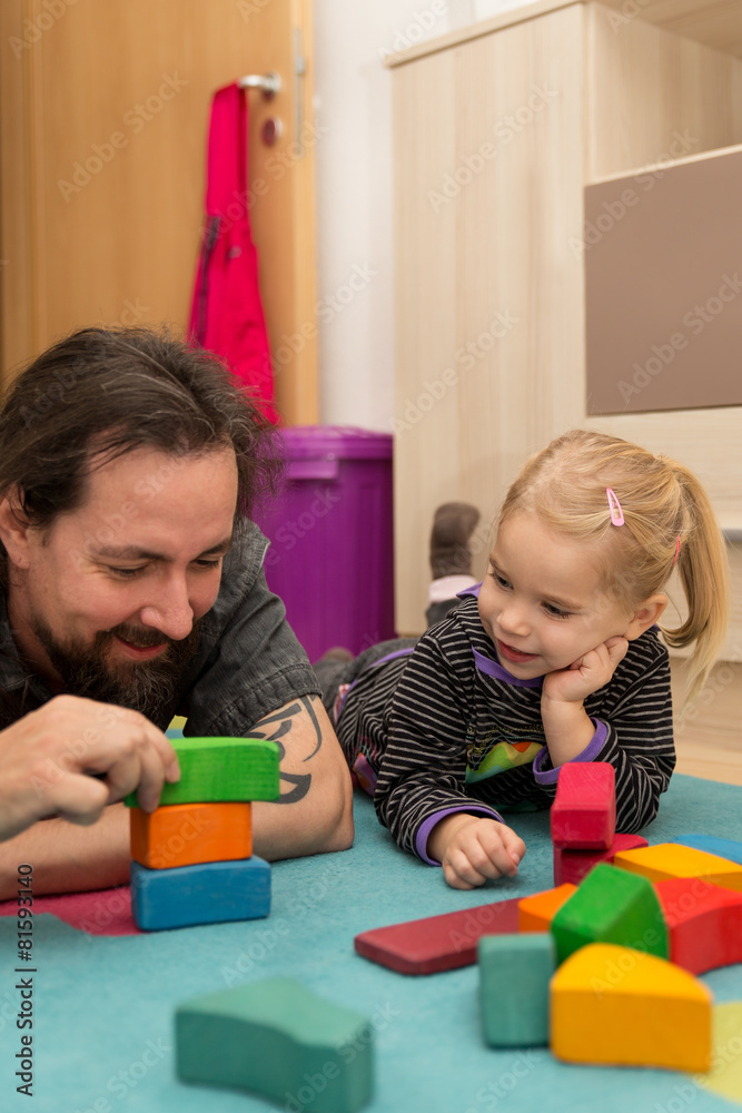 Vater und kleines Mädchen spielen mit bunten Bauklötzen