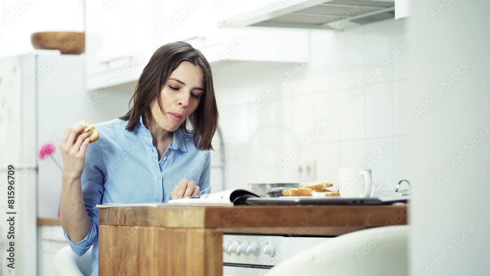 pretty woman reading newspaper and drinking water in kitchen pretty woman reading newspaper and drinking water in kitchen