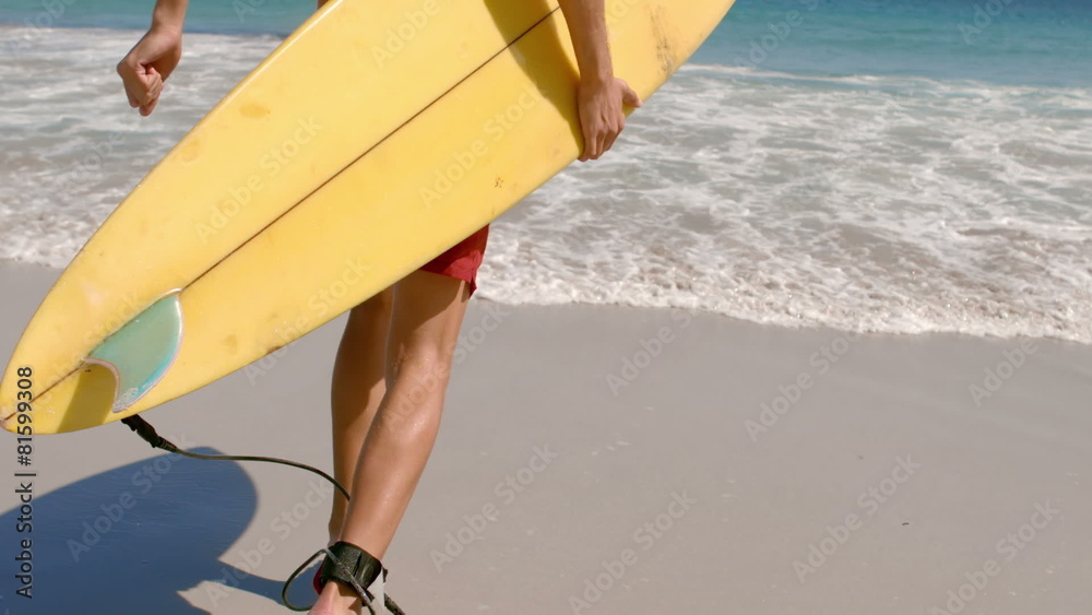 Handsome man running in the water with surfboard