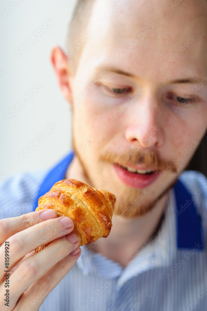 Young man eating croissant
