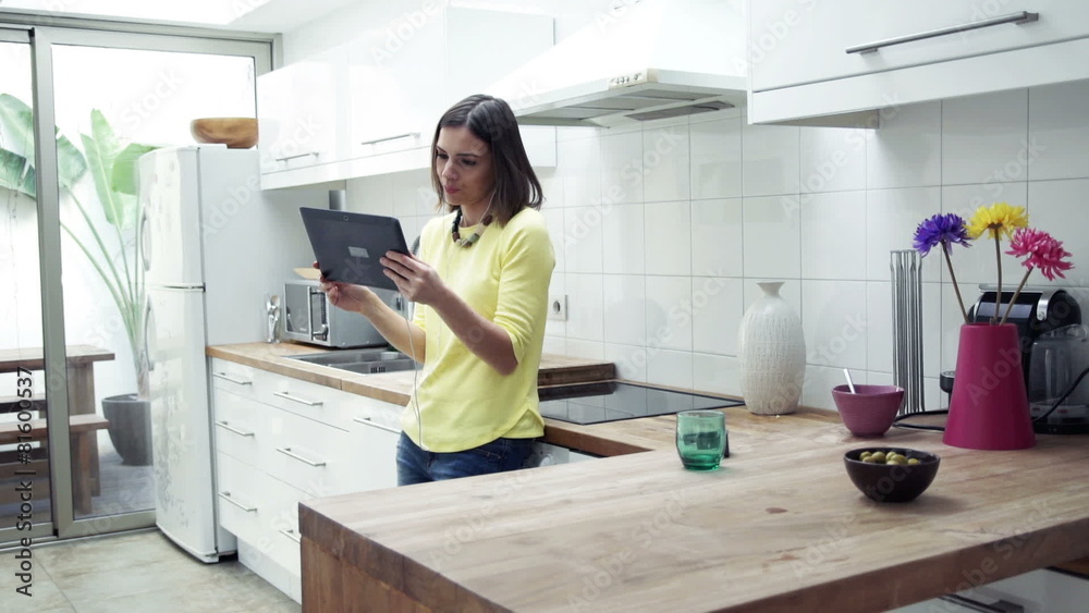 Happy woman watching movie on tablet computer in kitchen Happy woman watching movie on tablet computer in kitchen