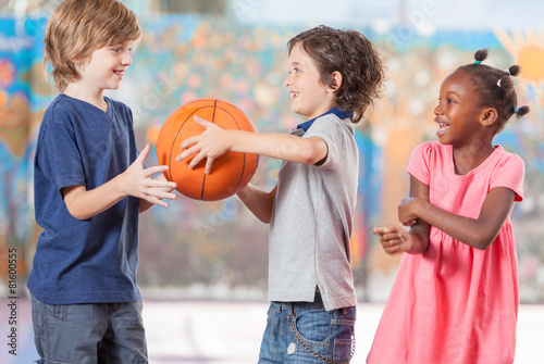 Happy multi ethnic children playing basketball at school