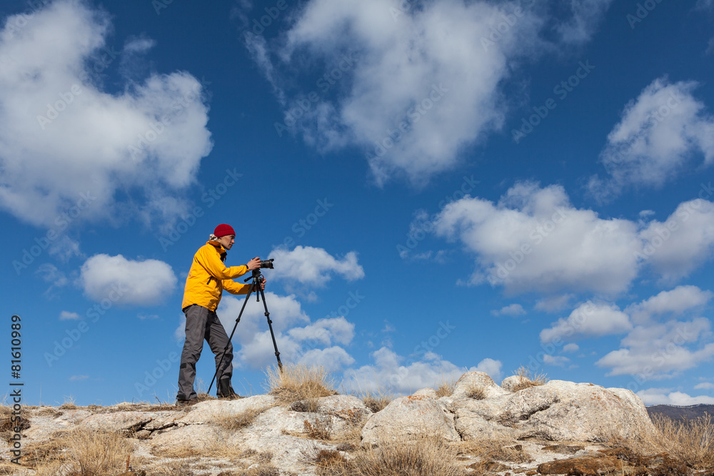Photographer is taking picture using tripod against cloudy sky