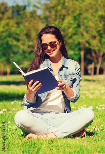 smiling young girl with book sitting in park