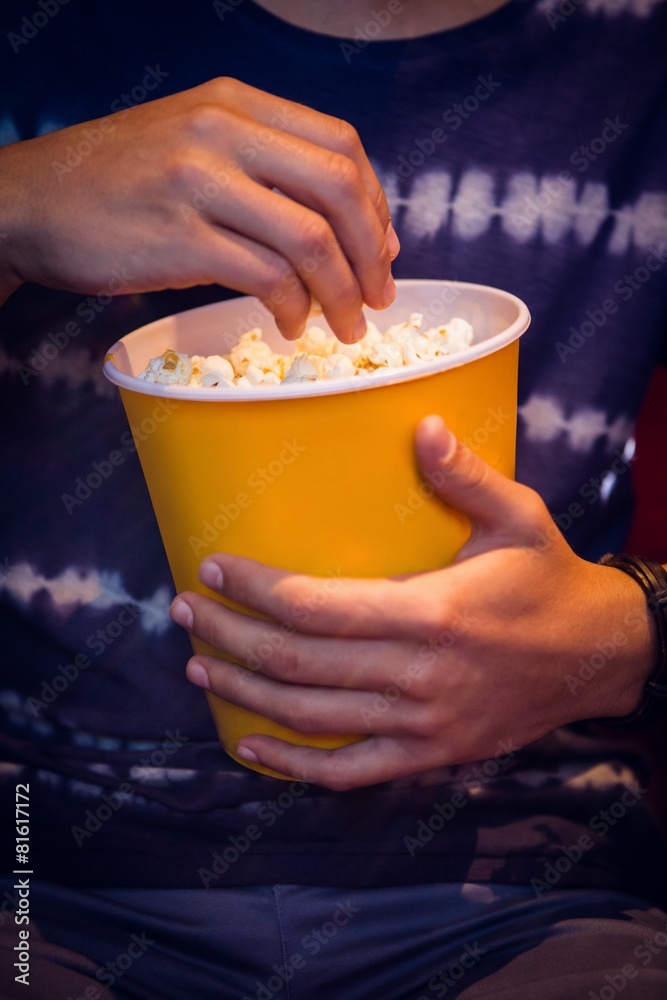 Young man watching a film and eating pop corn Young man watching a film and eating pop corn