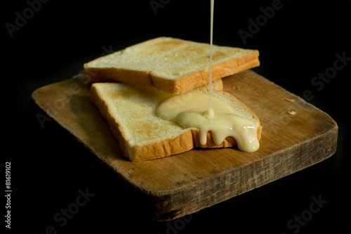 Foto Sliced toast on chopping wood block and isolated on black background