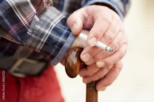 Hands with cigarette on cane