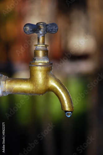 bronze faucet and a drop of water on a blurred background