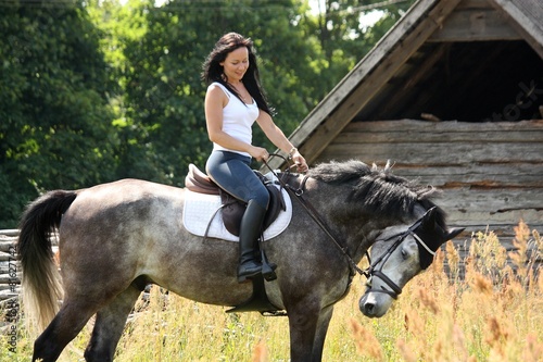 Portrait of beautiful woman on horse near the barn