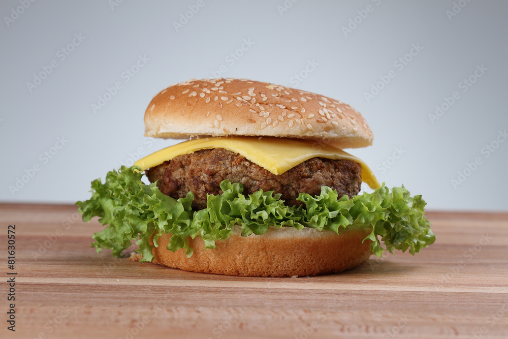 Hamburger with grilled meat and cheese on a wooden surface 

