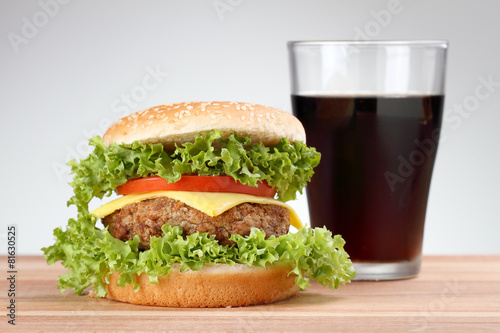 Hamburger with grilled meat and cheese on a wooden surface
