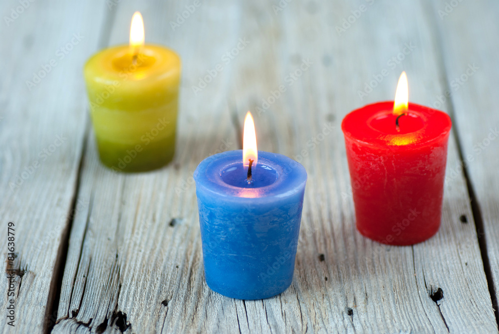 Colorful burning candles on old wooden table Colorful burning candles on old wooden table