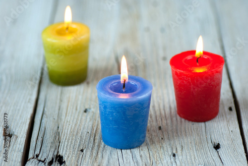 Colorful burning candles on old wooden table