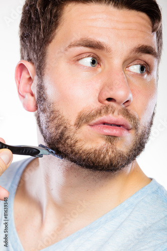 Young man with beard holding razor blade