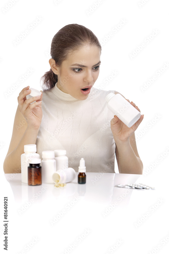 Beautiful surprised young woman looking into the pill bottle Beautiful surprised young woman looking into the pill bottle