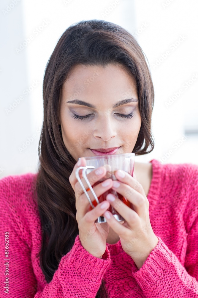 Smiling beautiful brunette holding cup on couch Smiling beautiful brunette holding cup on couch