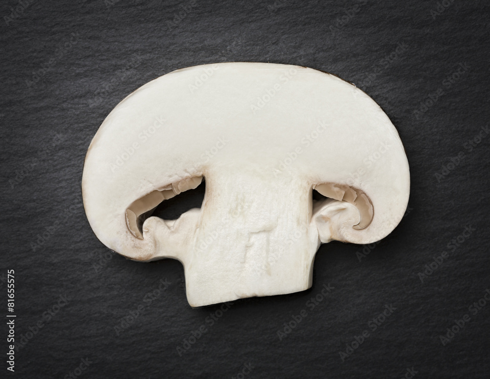 Fototapeta premium Cut champignon isolated on dark gray flagstone.
