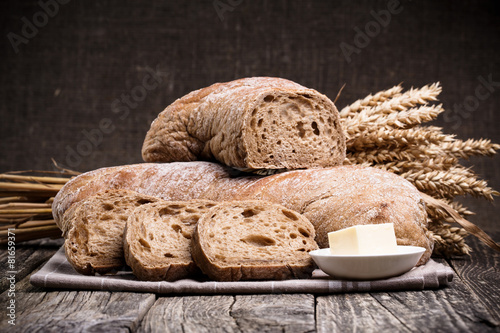 Tasty bread with wheat on wooden background.