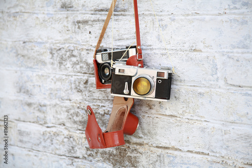 пара ретро фотоаппаратов на фоне стены