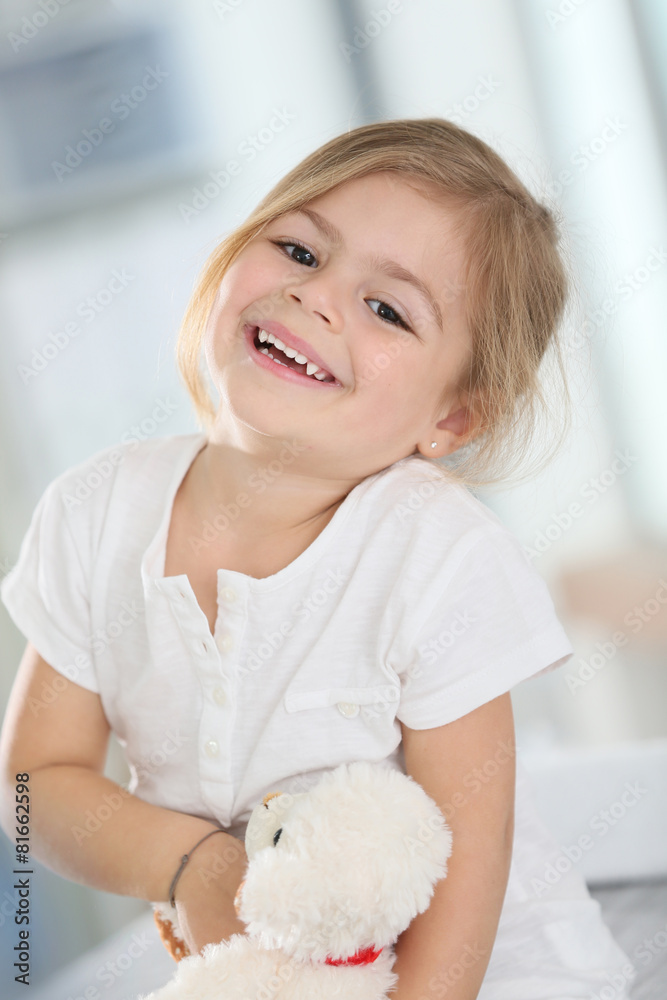 Fototapeta premium Portrait of cute blond little girl hugging teddy