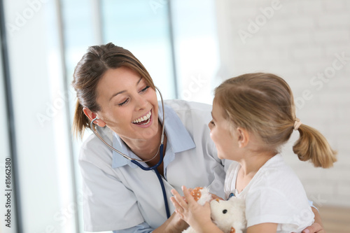Doctor examining little girl with stethoscope photo