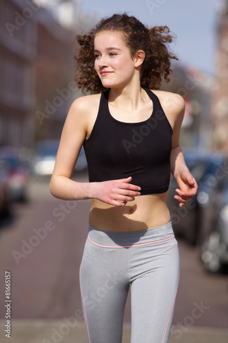 Happy teenage girl jogging outdoors
